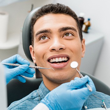 Man in denim shirt smiling at dentist about to examine his mouth