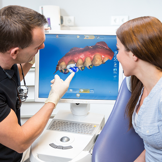 Dentist showing a patient a model of their teeth on a screen