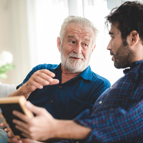 Young man and older man sitting on couch and talking