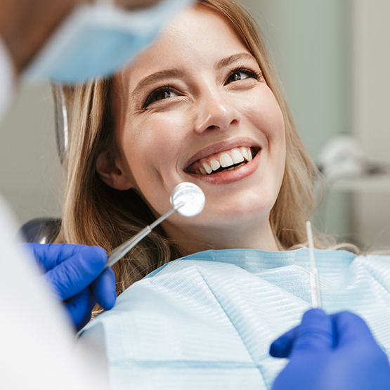 Woman in dental chair grinning at her dentist