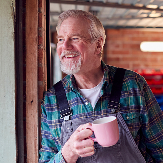 Senior man holding coffee mug and looking out of a window