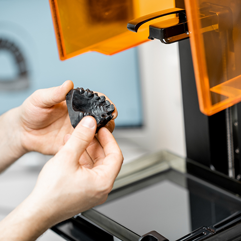 Hand holding a 3 D printed denture made with advanced dental technology in Reno