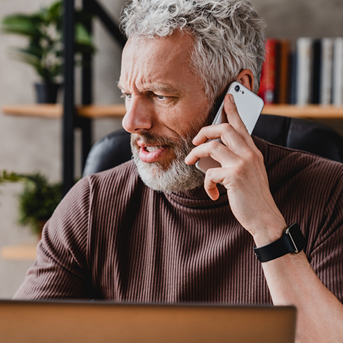 Man looking concerned while talking on phone with emergency dentist in Reno