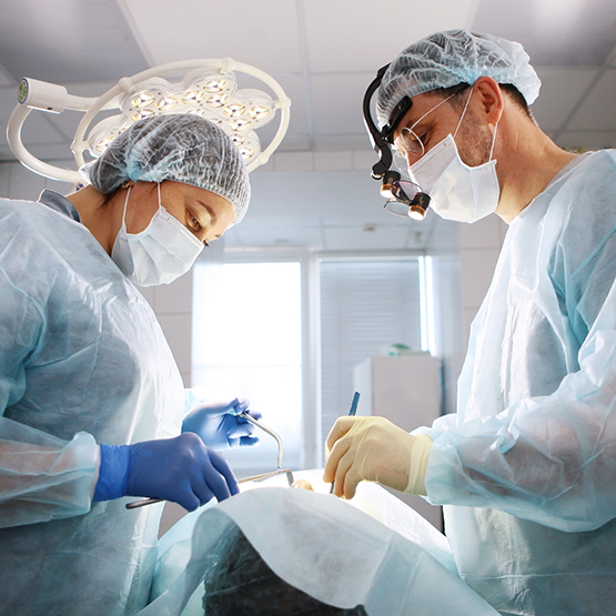 Oral surgeon and assistant performing dental implant surgery