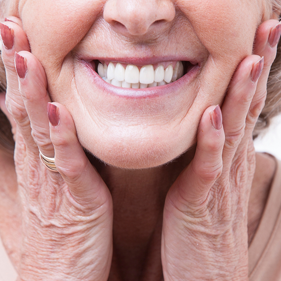 Smiling senior woman touching her face