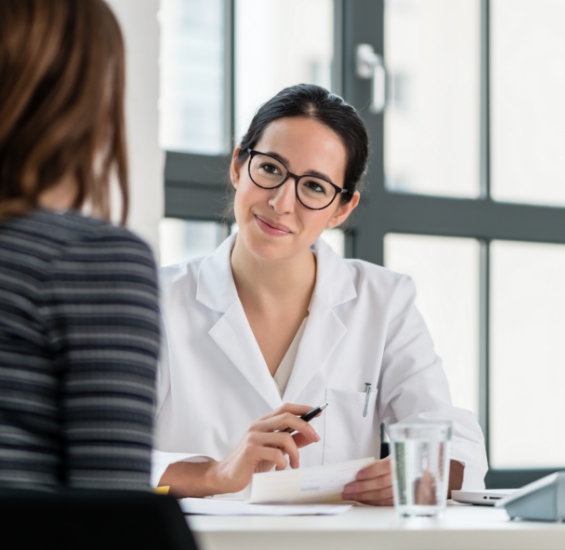 Dental team member with clipboard sitting across table from patient