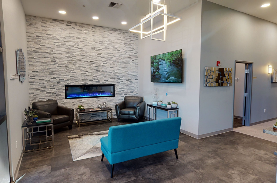 Couches and T V mounted on the wall of reception area of Smile Design Implant Centers