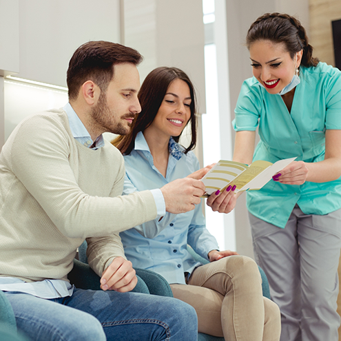 Dental team member showing a pamphlet to two patients