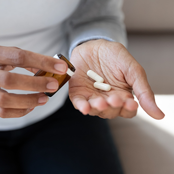 Person pouring pills out of bottle and into their hand