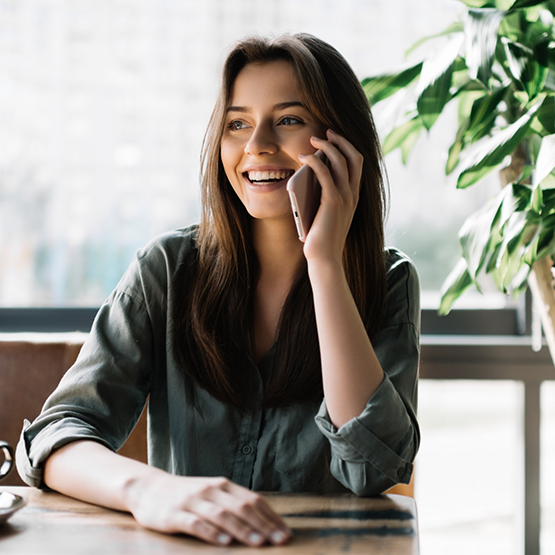 Smiling woman sitting at desk and talking on phone