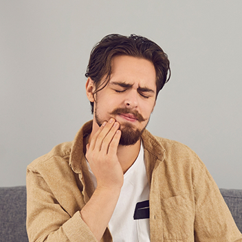 Man wincing and holding his jaw