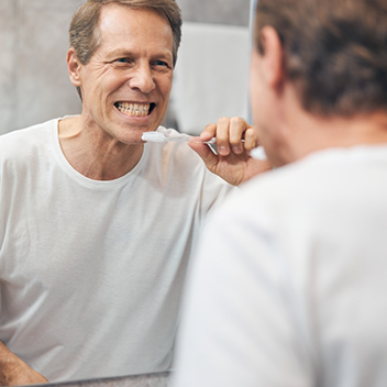 Man brushing his teeth in front of mirror