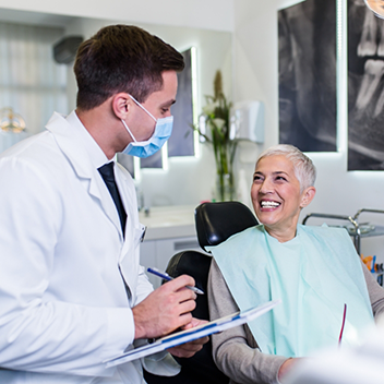 Senior woman in dental chair grinning at her dentist