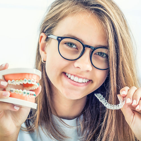 Smiling young woman holding a Sure Smile clear aligner in Reno