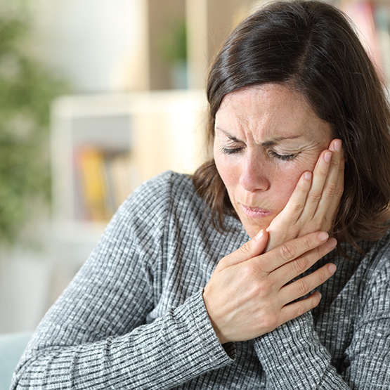 Woman wincing and holding her cheek in pain